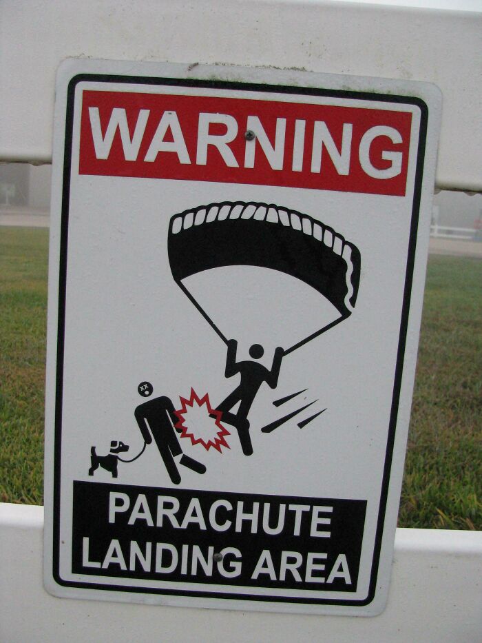 Warning sign for parachute landing area showing a person hitting another while parachuting, a bizarre and hilarious sign concept.