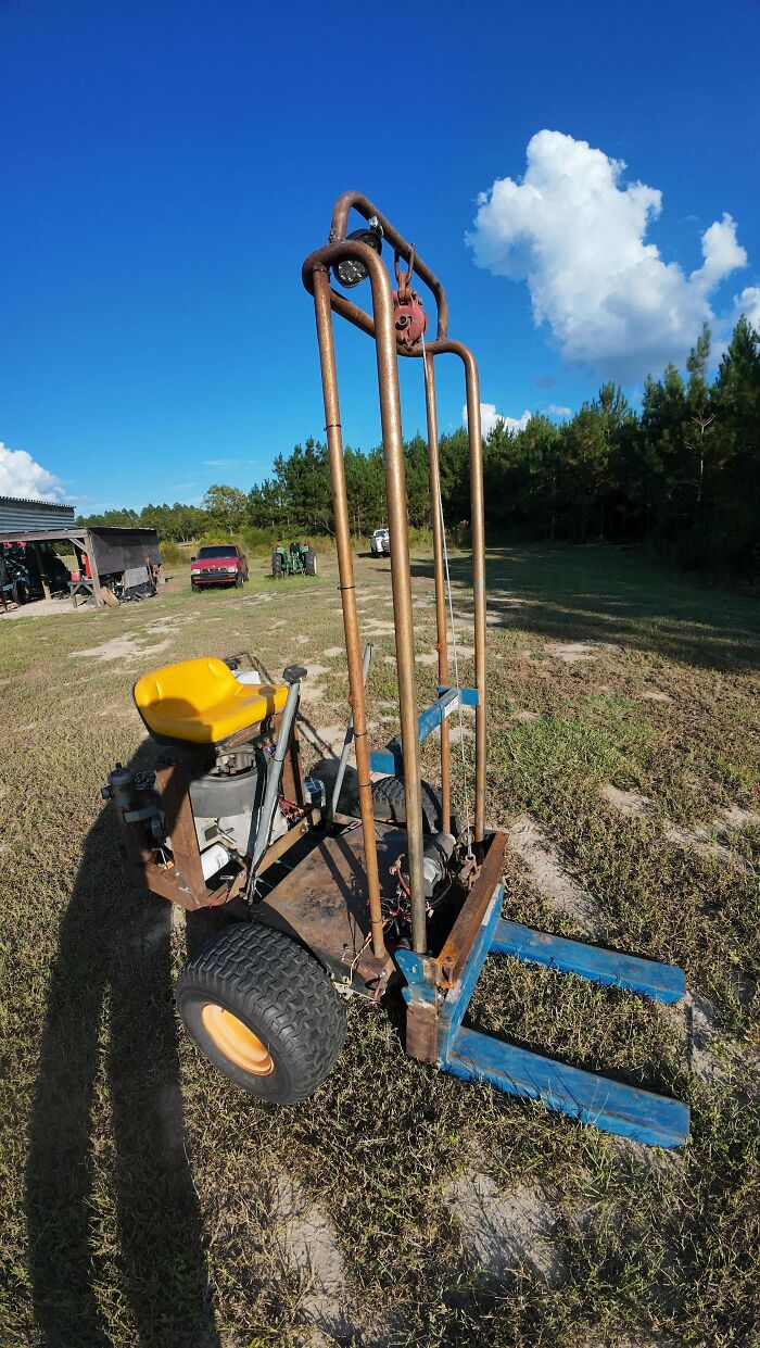 Homemade forklift with a yellow seat and rusted metal frame, an example of redneck engineering in an outdoor rural area.