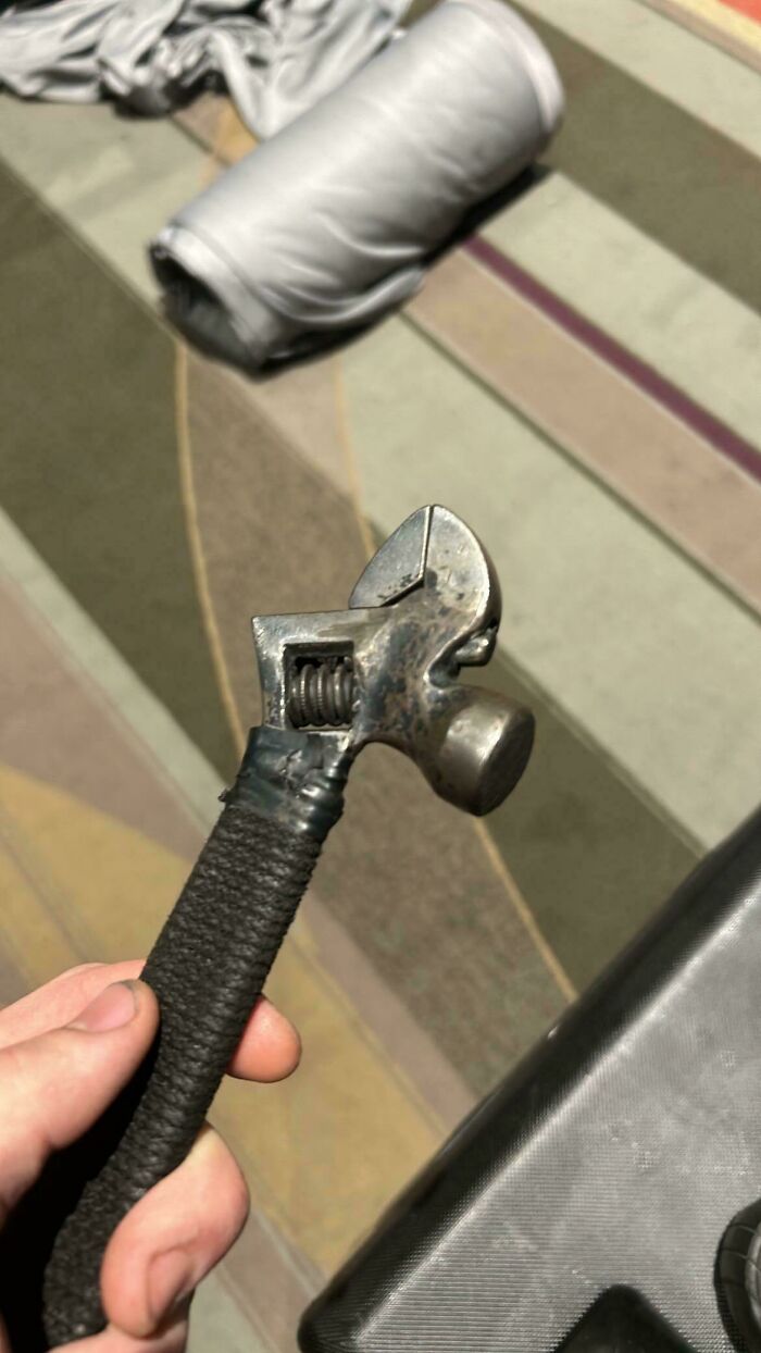 Close-up of a homemade tool combining a wrench and hammer handle wrapped in black tape, showcasing redneck engineering.