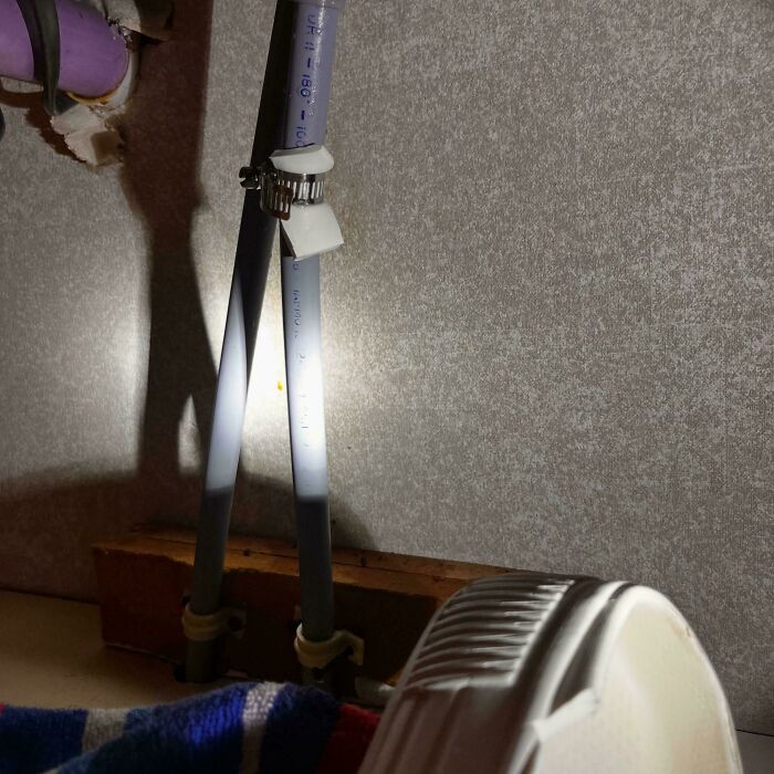 PVC pipes connected with a metal clamp and tape in a makeshift setup illustrating redneck engineering fails.
