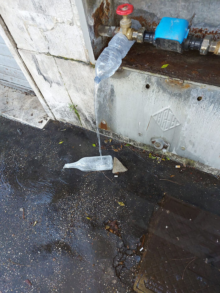 Plastic bottle attached to outdoor valve for a makeshift water flow setup, showing redneck engineering creativity outdoors.