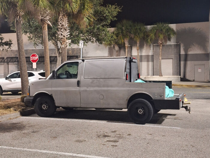 Old van in a parking lot modified with a makeshift pickup truck bed showcasing redneck engineering creativity.