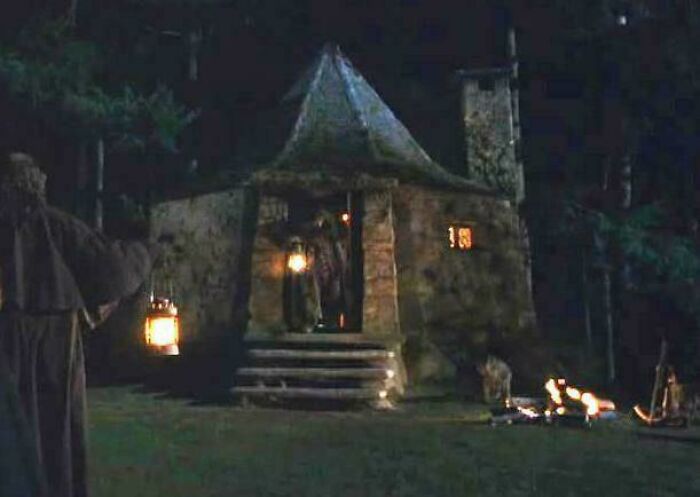 A rustic stone cabin lit by lanterns and campfire at night, illustrating absurd movie and TV details made up yet accurate.