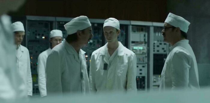 Scientists in white lab coats and caps working with complex equipment, illustrating absurd movie and TV details.