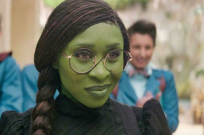 Green-skinned woman with glasses in a costume, illustrating hilariously absurd movie and TV details that are made up yet accurate.