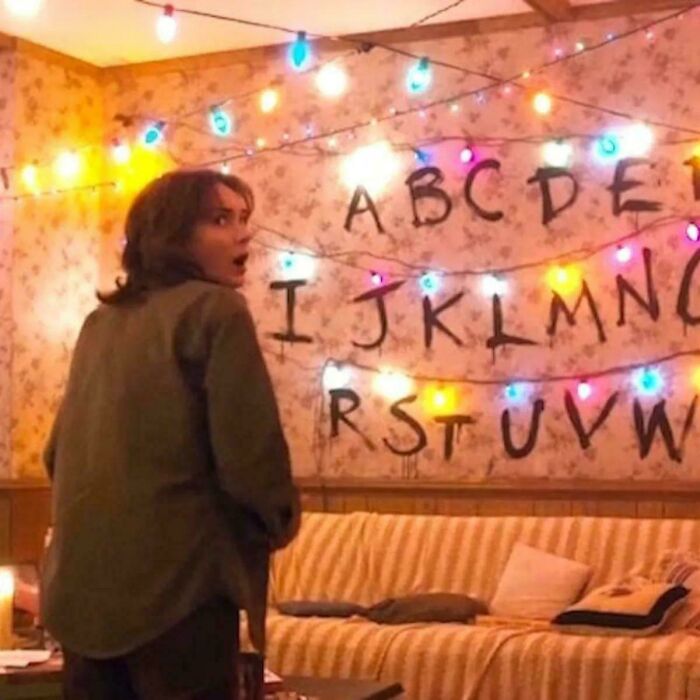 Person looking surprised inside a room with alphabet letters and colorful lights, illustrating absurd movie and TV details.