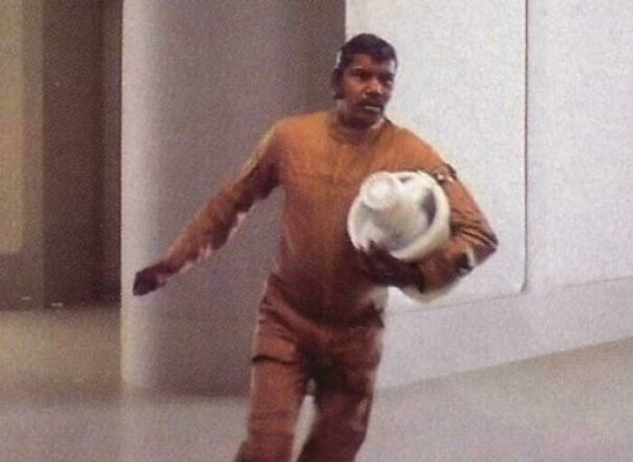 Man in brown outfit holding a futuristic helmet, illustrating hilariously absurd movie and TV details made up yet accurate.