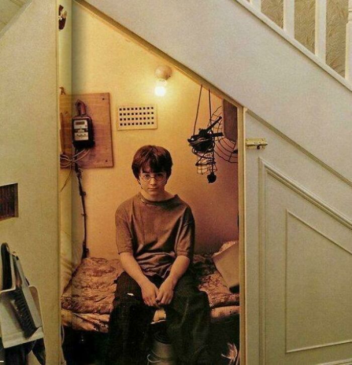 Young boy sitting under stairs in a small room, representing absurd movie and TV details that seem oddly accurate.