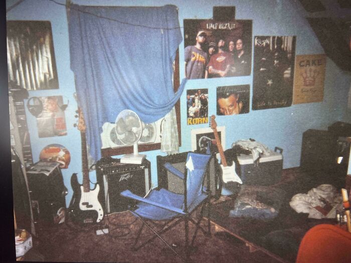 90s childhood bedroom with band posters, electric guitars, amplifier, and a folding chair in a nostalgic setting.