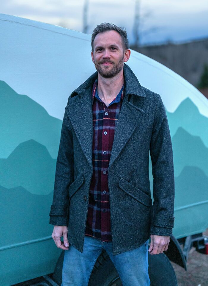 Man standing outdoors in front of a painted camper, showcasing DIY wins and healing through creative projects.
