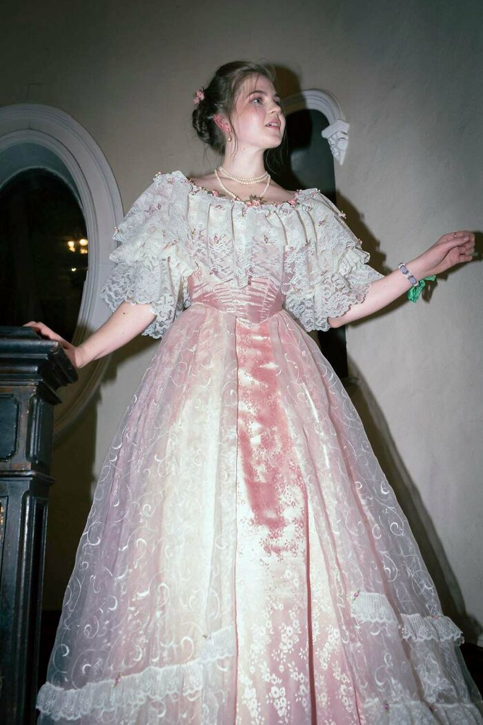 Young woman in a vintage style pink and white lace DIY dress, showcasing a creative win in home sewing and crafting.