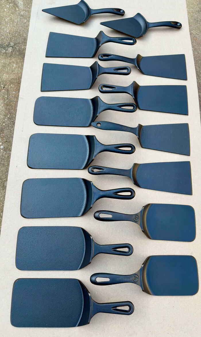 Set of black cast iron spatulas arranged on a cardboard surface showing DIY wins in tool restoration.