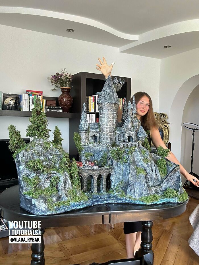 Person showcasing a detailed DIY castle model with greenery and rocky terrain, highlighting creative DIY wins.