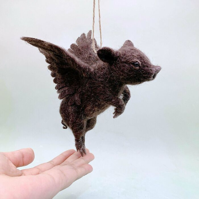 Hand holding a DIY felted flying pig ornament, showcasing creative DIY wins and handmade craft skills.