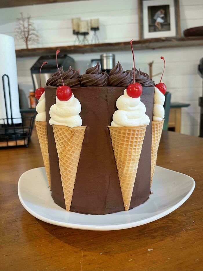 Chocolate cake decorated with ice cream cones, whipped cream, cherries, showcasing a creative DIY win dessert.