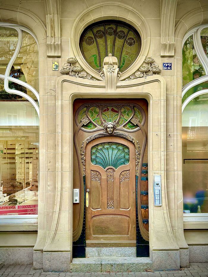 An ornate wooden door with intricate carvings and stained glass, set within a stone facade, displaying beautiful architecture.
