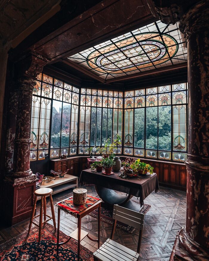 Cozy sunroom with stained glass windows, potted plants, and wooden details, highlighting beautiful architecture.
