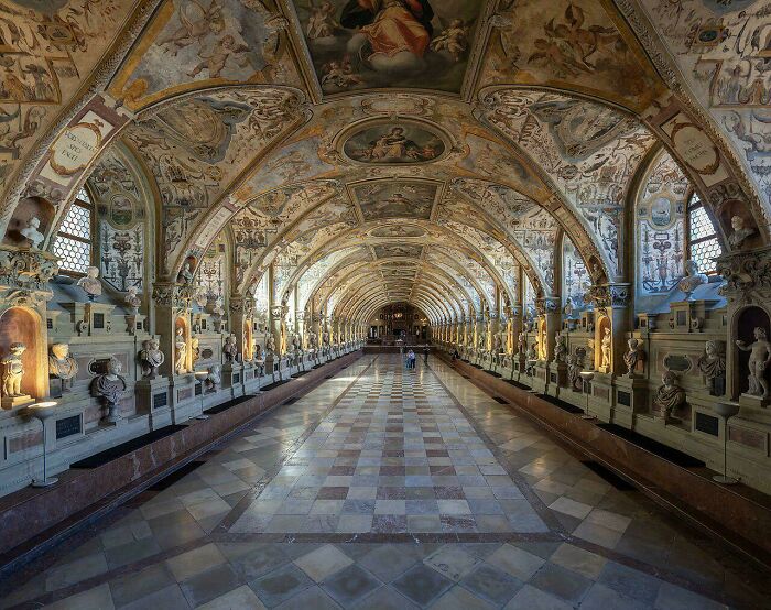 Long vaulted hall with beautiful architecture, featuring detailed frescoes and numerous busts in alcoves.