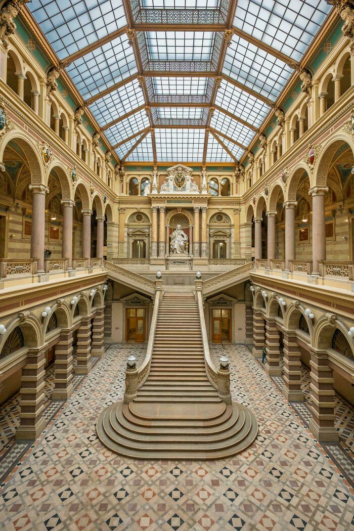 Grand interior with beautiful architecture, showcasing a majestic staircase, columns, and a glass ceiling.