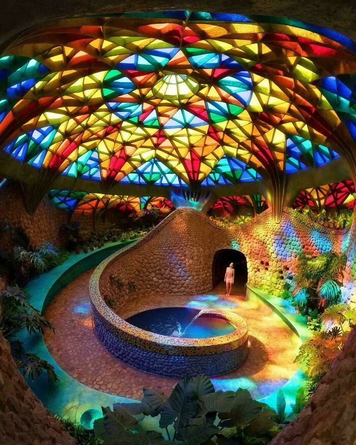 Modern architecture with a vibrant stained-glass dome illuminating a spiral path and indoor garden.