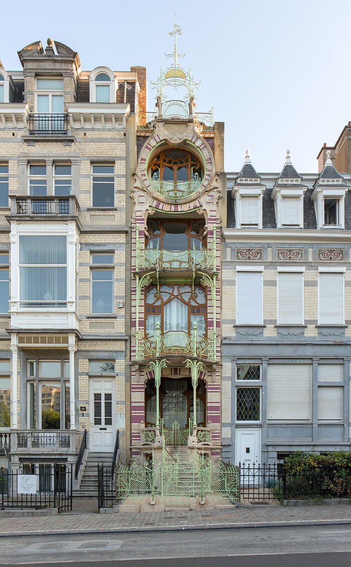 Elegant Art Nouveau architecture with intricate metalwork and decorative patterns on a narrow building facade.