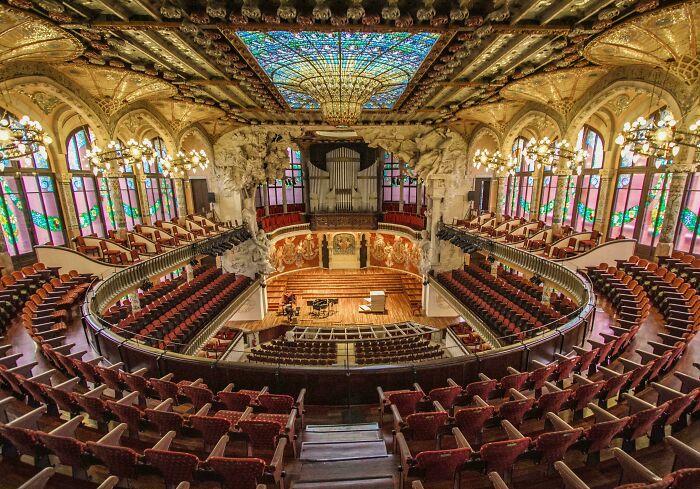 An ornate concert hall with stained glass and detailed ceilings, a stunning example of beautiful architecture.