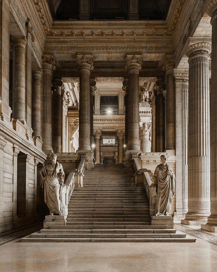 Inside a majestic building with a grand staircase and numerous columns, an example of beautiful architecture.