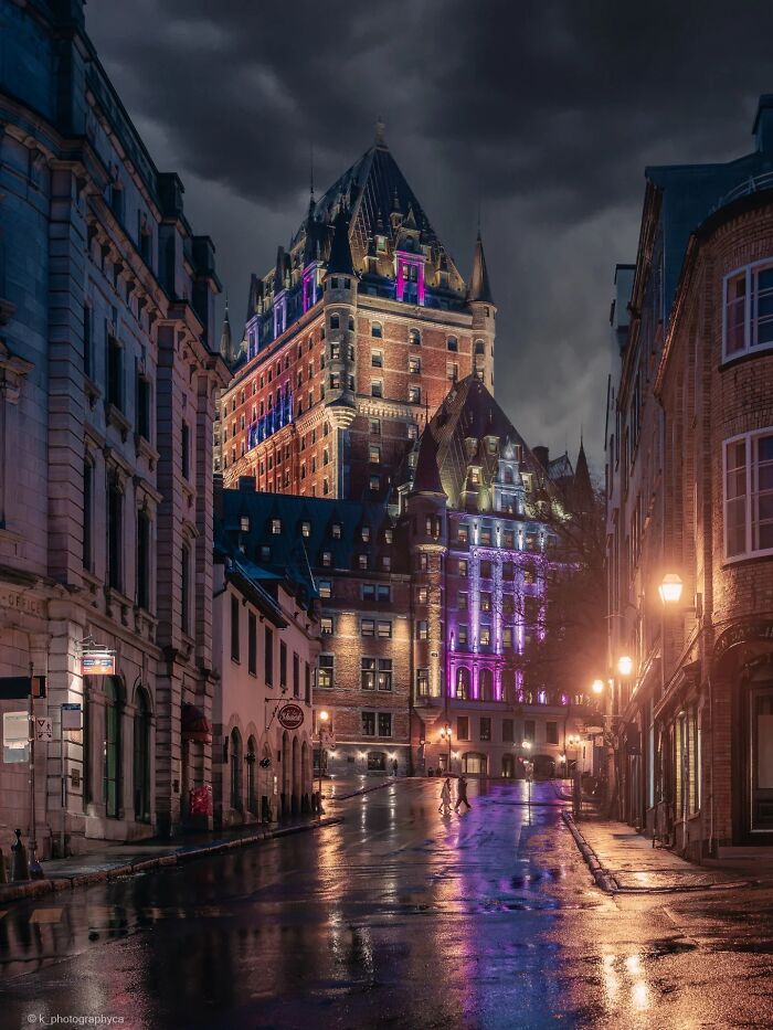 Château Frontenac, an example of beautiful architecture, illuminated at night on a wet street.