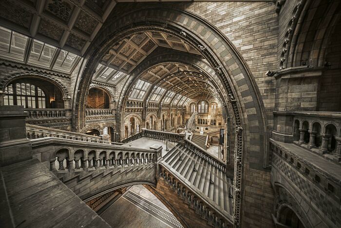 Interior view of a grand hall with arched ceilings and elaborate staircases, featuring beautiful architecture.