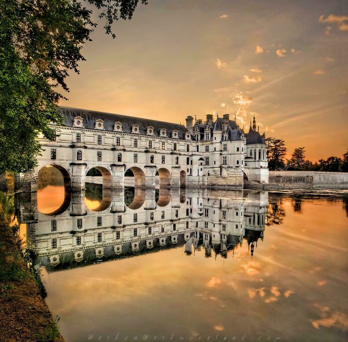 Stunning Château de Chenonceau, beautiful architecture reflected in the water at sunset.