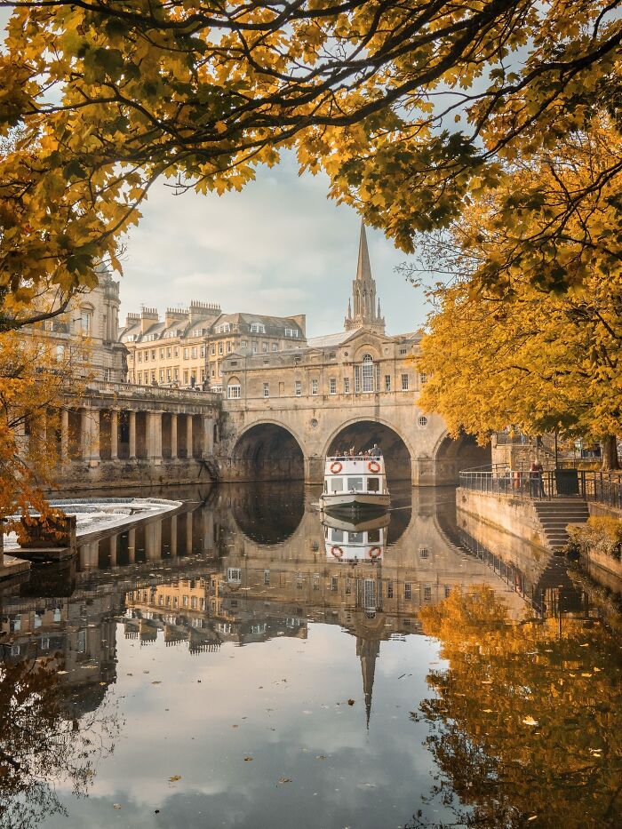 Beautiful architecture of Pulteney Bridge over the River Avon, framed by golden autumn trees.