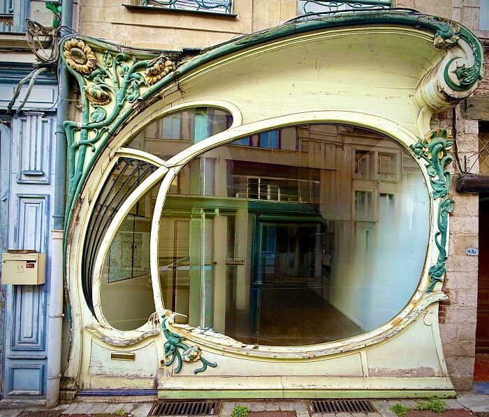 Art Nouveau storefront architecture with decorative floral elements and a large curved window.