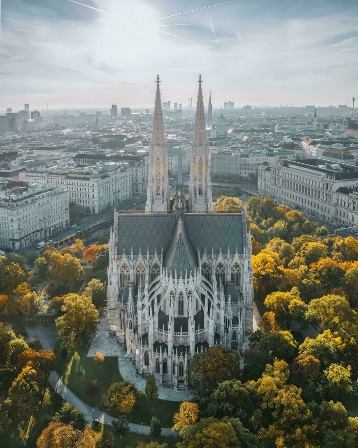 An aerial view of beautiful architecture, a majestic cathedral with twin spires surrounded by autumn trees and a city.