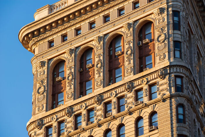 Beautiful architecture: Close-up of an ornate building corner with detailed carvings and arched windows, bathed in golden light.