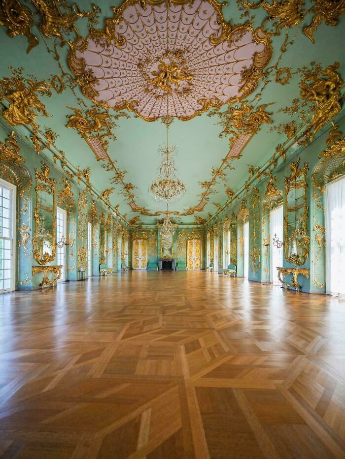 Luxurious hall with ornate gold embellishments on teal walls and ceiling, a stunning example of beautiful architecture.