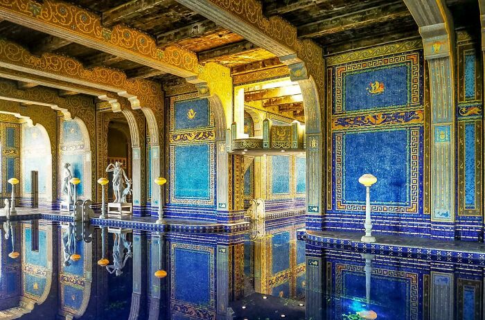 Beautiful architecture: Ornate indoor pool with blue and gold mosaic tiles and sculptures reflecting in the water.