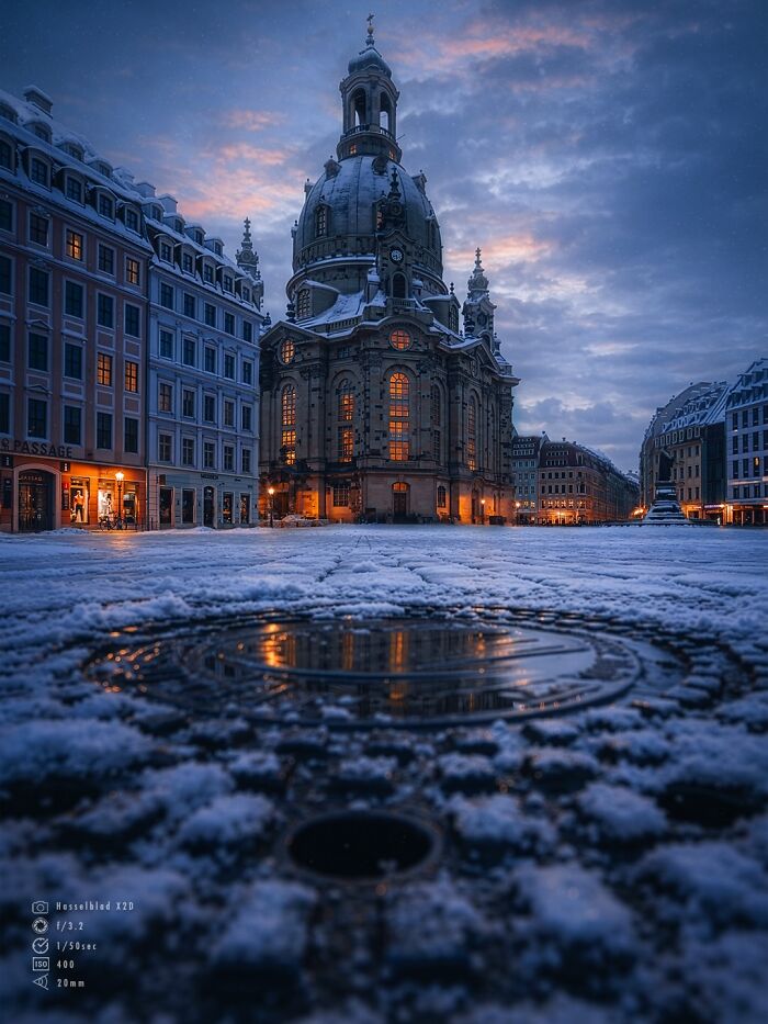 Beautiful architecture: Dresden Frauenkirche at dusk, illuminated with warm lights, surrounded by snow.