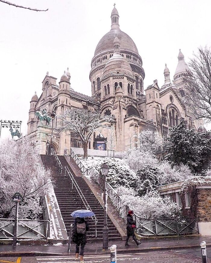Beautiful architecture: Sacré-Cœur Basilica in Paris covered in snow, with people walking below.