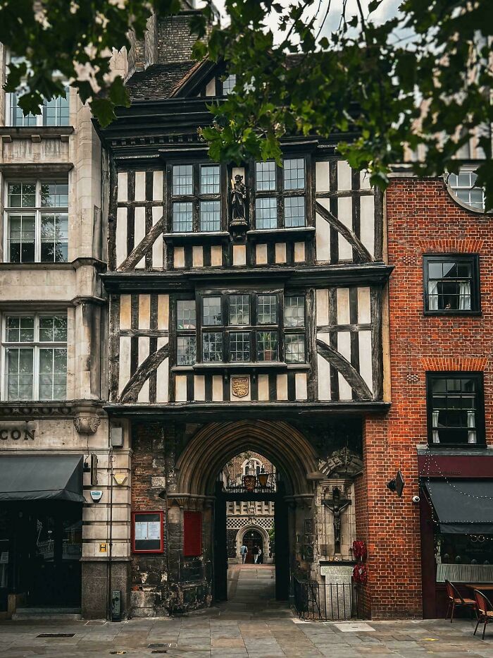 Historic, beautiful half-timbered architecture with an archway entrance, contrasting with a brick building next to it.