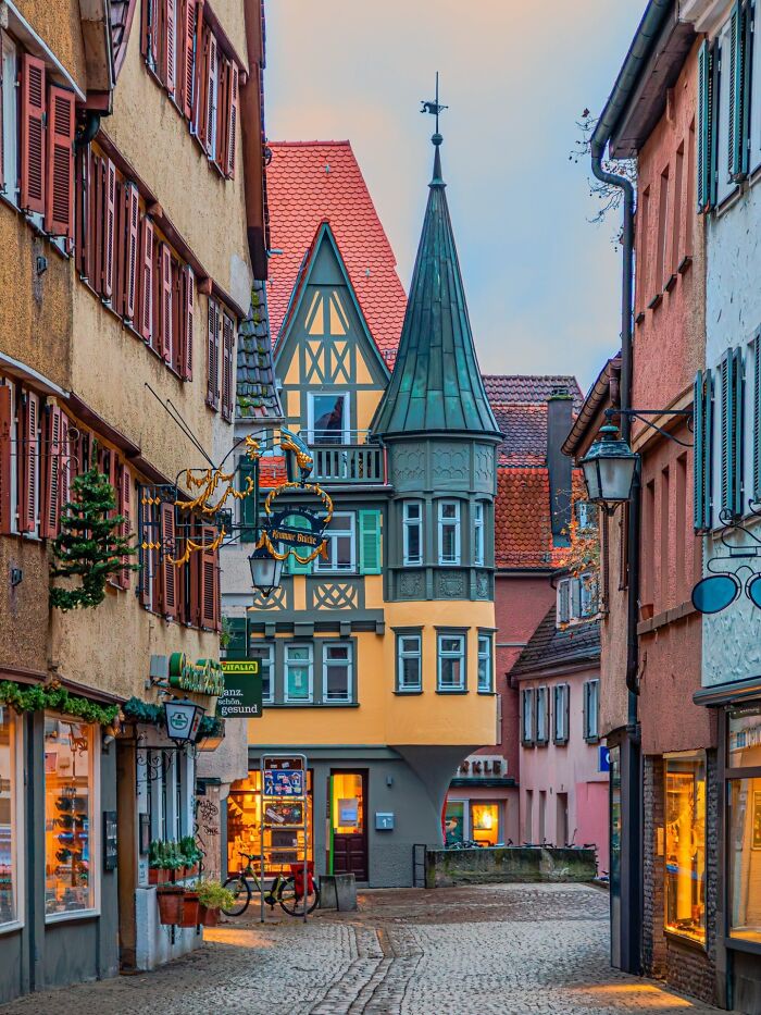 Charming, beautiful architecture of a narrow European street with colorful buildings and a unique pointed tower.