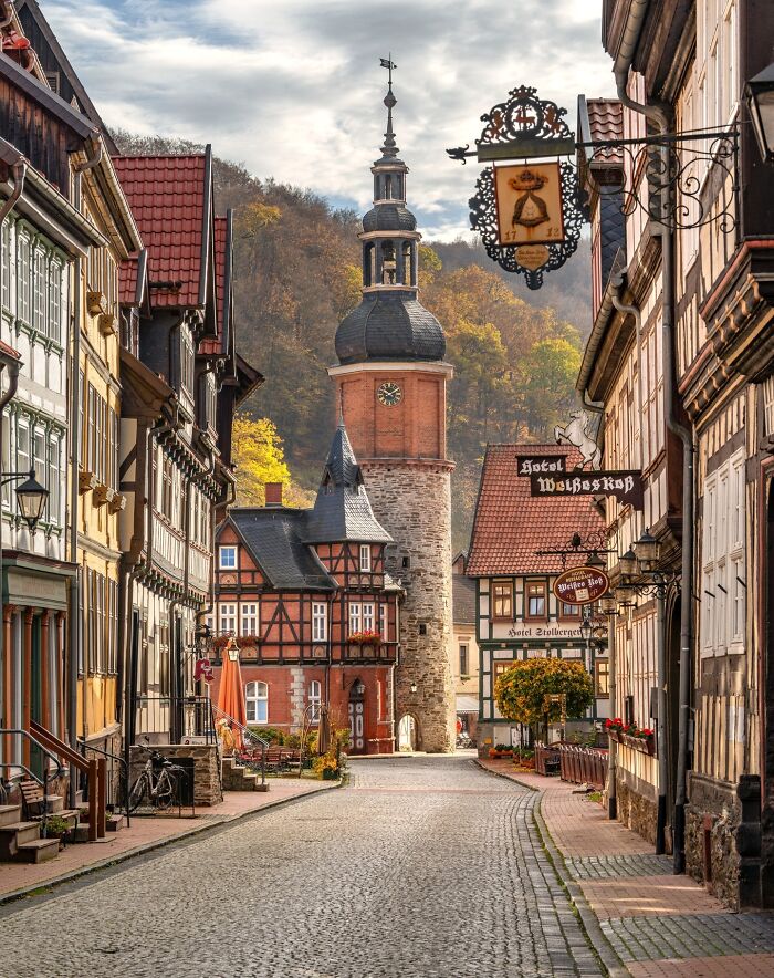 Picturesque street with historic half-timbered architecture and a prominent clock tower in a charming town.