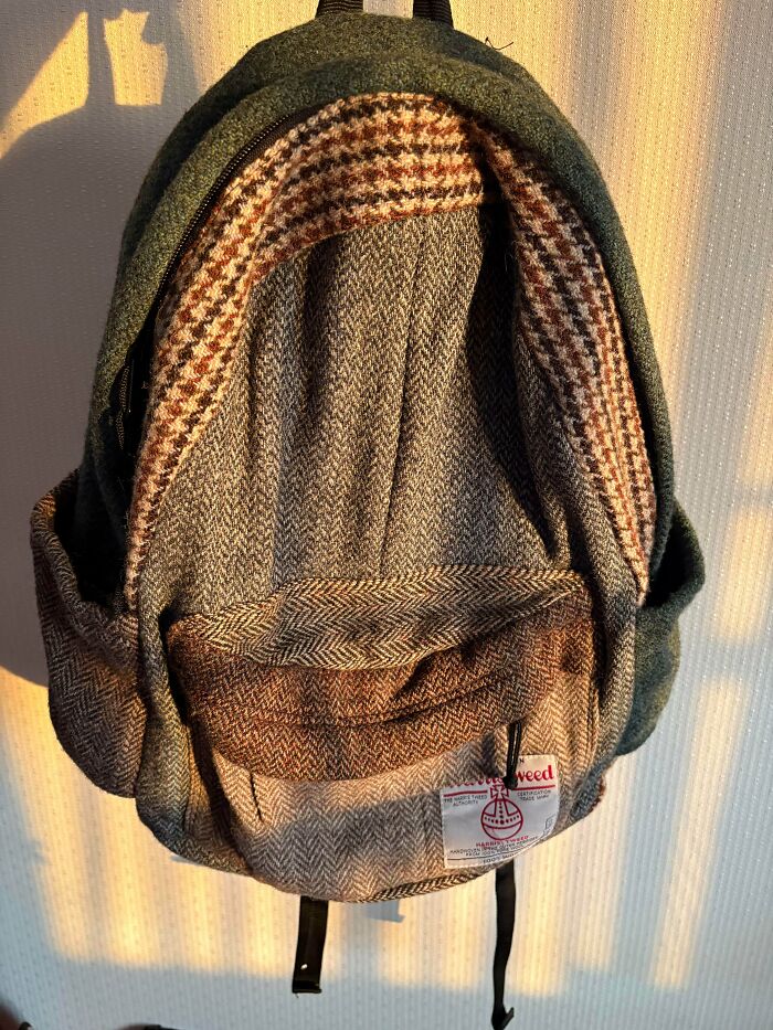 Wool fabric backpack with herringbone and plaid patterns, a unique thrift store find in warm sunlight.