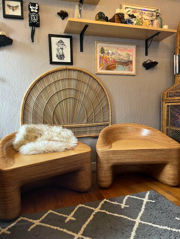 Two unique wooden chairs and a rattan headboard as thrift store finds in a cozy, vintage-inspired living space.