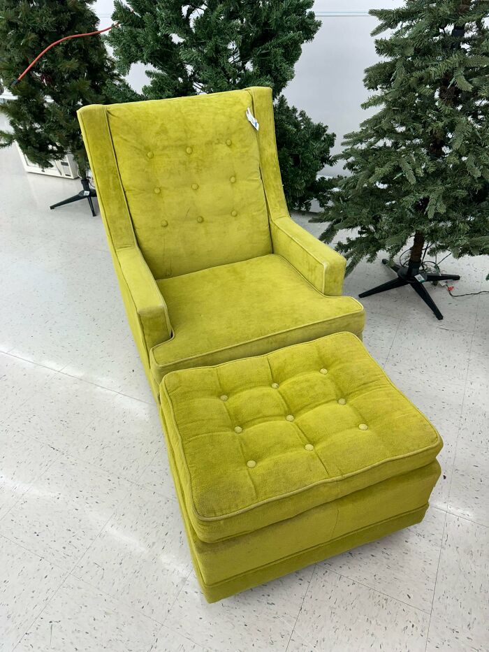 Green velvet tufted armchair with ottoman, a unique thrift store find displayed near artificial Christmas trees.