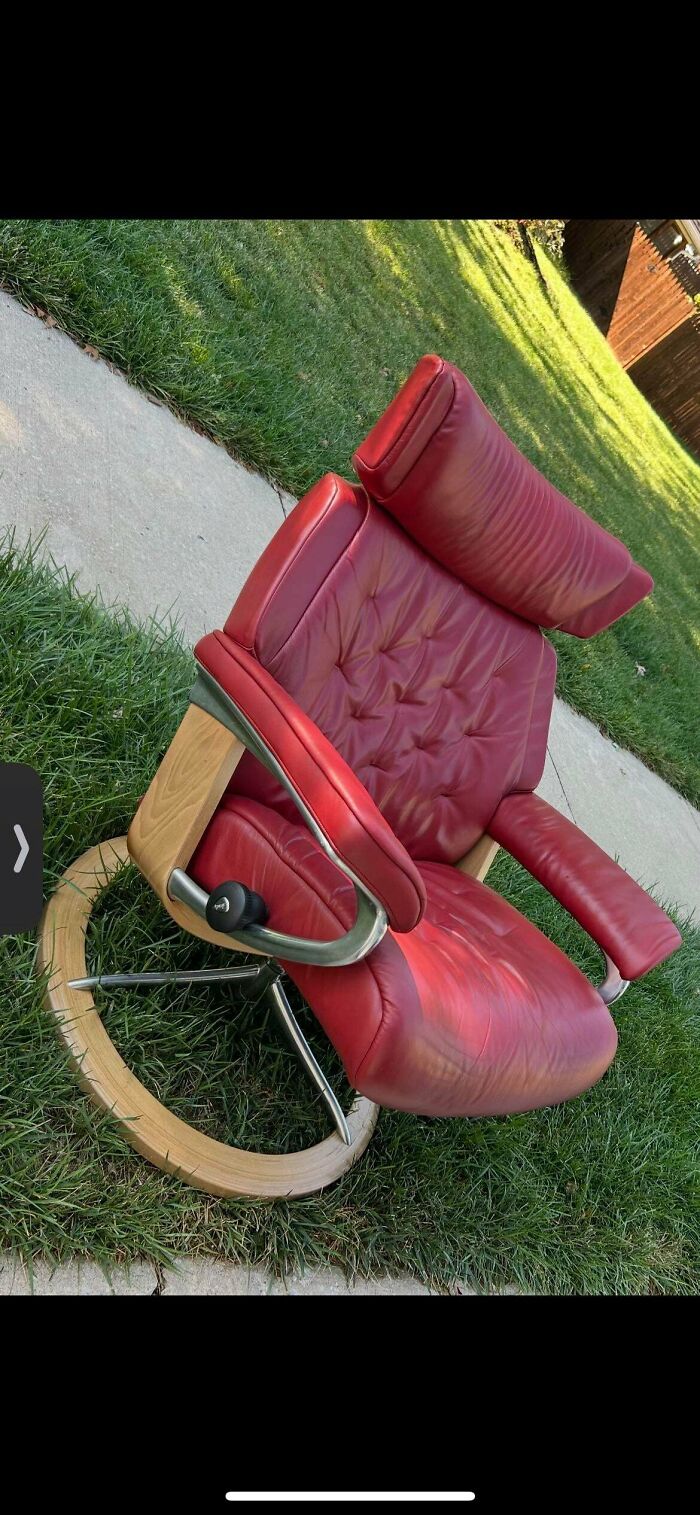 Red leather and wood swivel chair thrift store find on grass near sidewalk, showcasing unique vintage style and design.