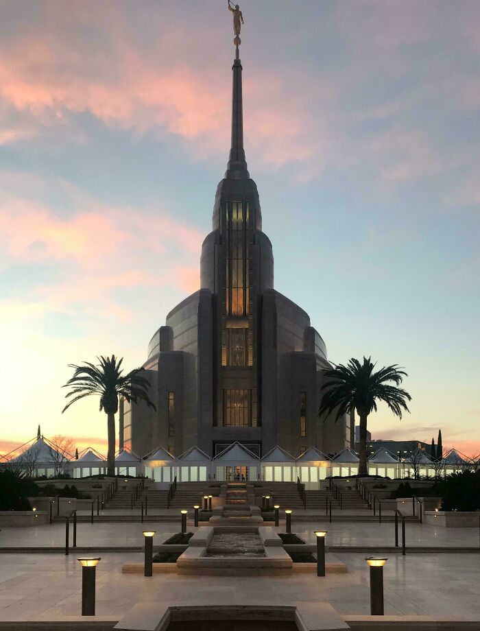 A majestic building that looks like it was built for an evil mastermind, with a tall spire at sunset.