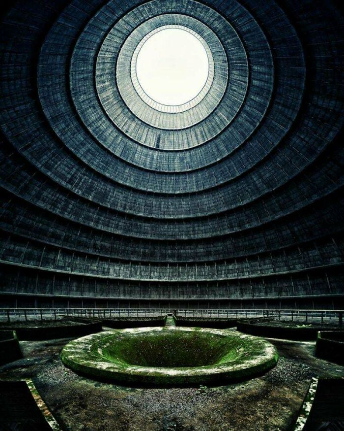 The dark, imposing interior of a round building with a central mossy pool, a perfect setting for an evil mastermind.