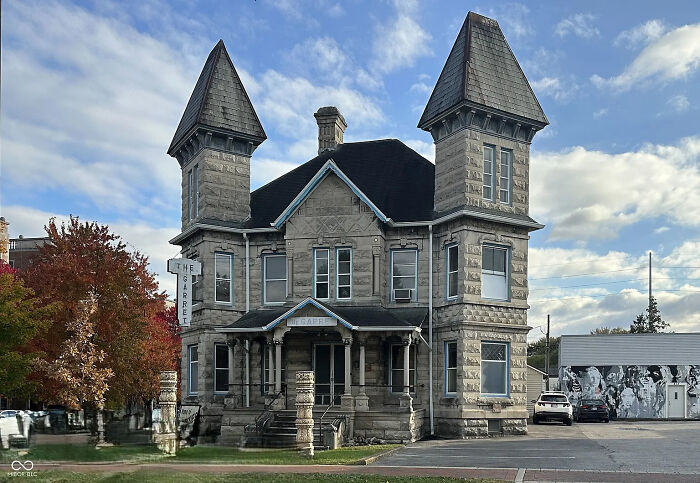 A grand, stone building with two spired towers, evoking an evil mastermind's lair, surrounded by autumn trees.