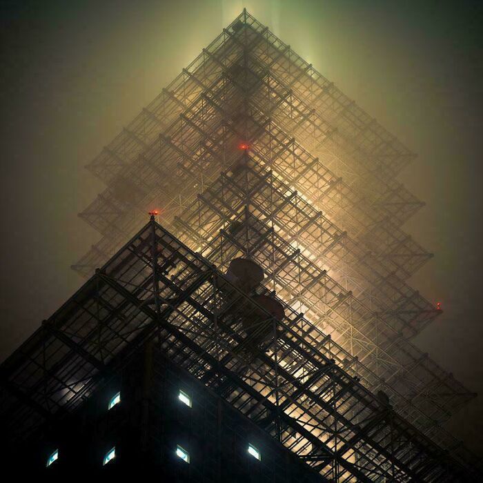 A mysteriously lit building resembling a pyramidal structure, shrouded in mist, built for an evil mastermind.