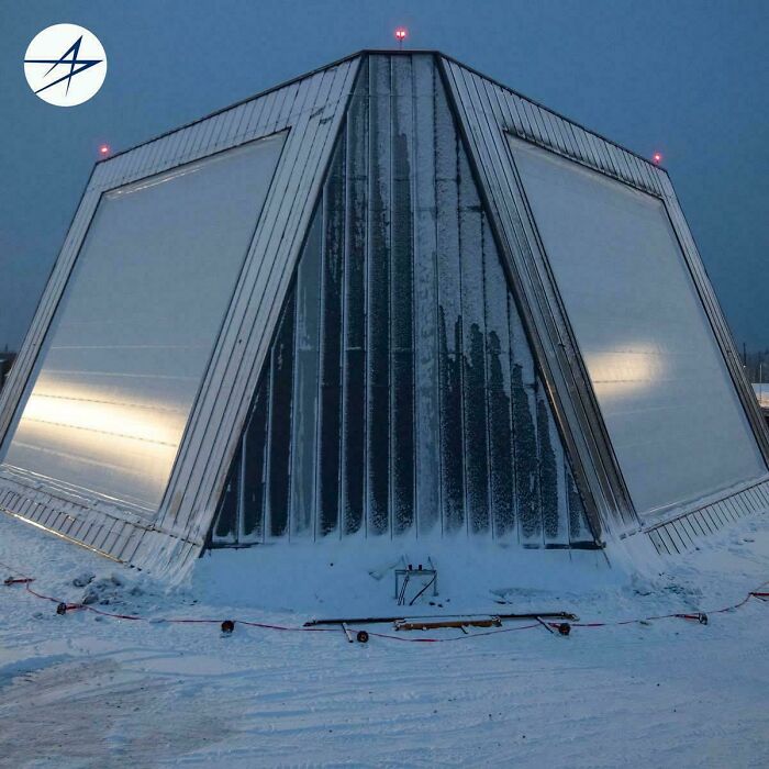 A stark, angular evil mastermind building covered in snow with red lights, perfect for planning world conquest.